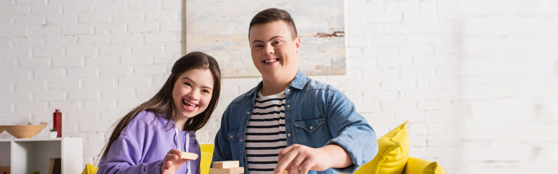 Happy friends with down syndrome looking at camera near wood blocks game at home